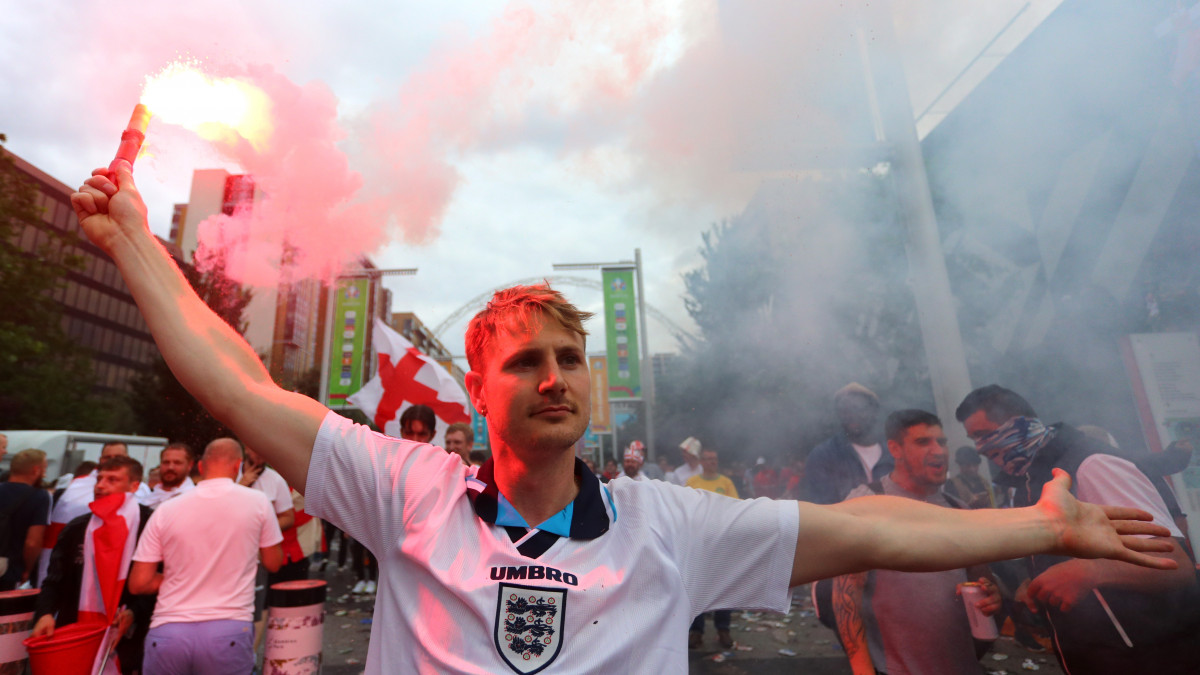LONDON, ENGLAND - JULY 11: An England fan holds a flare outside of the stadium during the UEFA Euro 2020 Championship Final between Italy and England at Wembley Stadium on July 11, 2021 in London, England. (Photo by Chloe Knott - Danehouse/Getty Images)