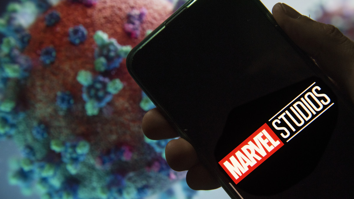 CHINA - 2020/03/27: In this photo illustration the American film production label owned by Disney, Marvel Studios, logo seen displayed on a smartphone with a computer model of the COVID-19 coronavirus on the background. (Photo by Budrul Chukrut/SOPA Images/LightRocket via Getty Images)