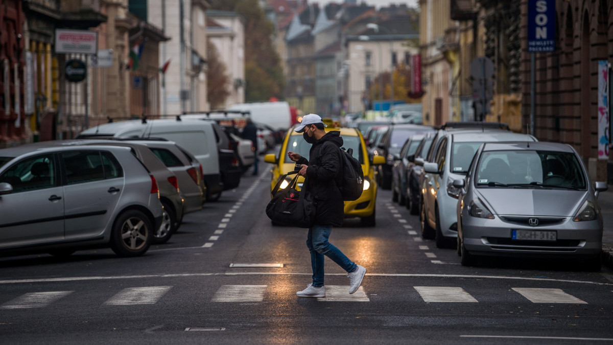 Védőmaszkot viselő járókelő a budapesti Rákóczi úton 2020. november 11-én. A koronavírus-járvány elleni kormányzati védelmi intézkedések új elemeként kötelező a maszkviselés a 10 ezernél több lakosú települések egyes közterületein; a területek kijelölése a polgármester feladata. Sporttevékenység során, valamint a parkokban, illetve zöldterületeken a maszk viselése továbbra sem kötelező.