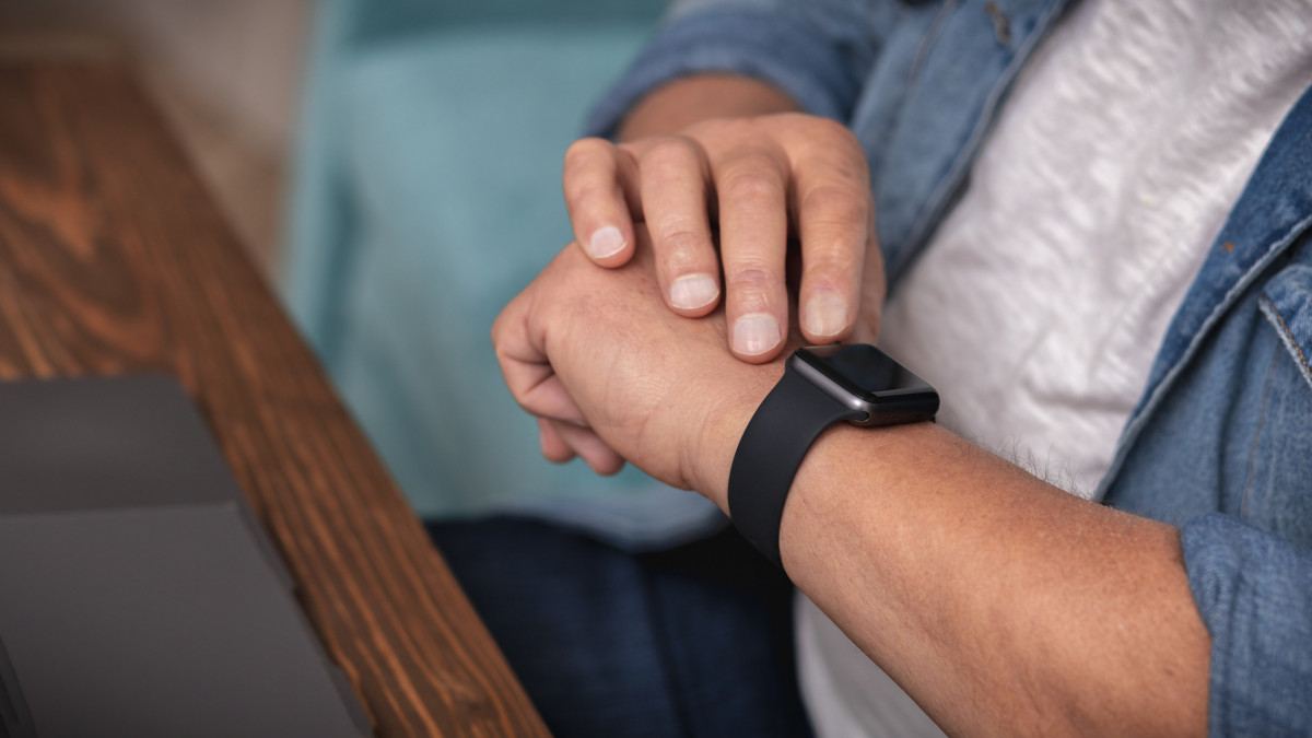Adult man monitors heart rate with smart watch on wrist