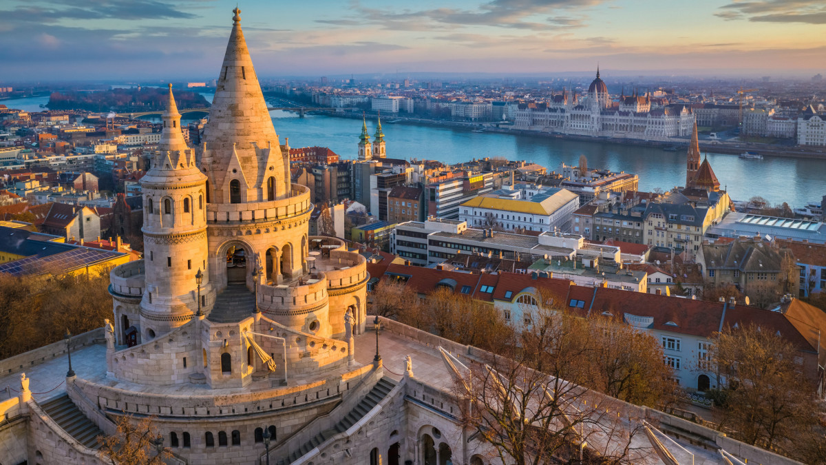 Budapest, Hungary - The main tower of the famous Fishermans Bastion (Halaszbastya) from above with Parliament building and River Danube at background on a sunny morning