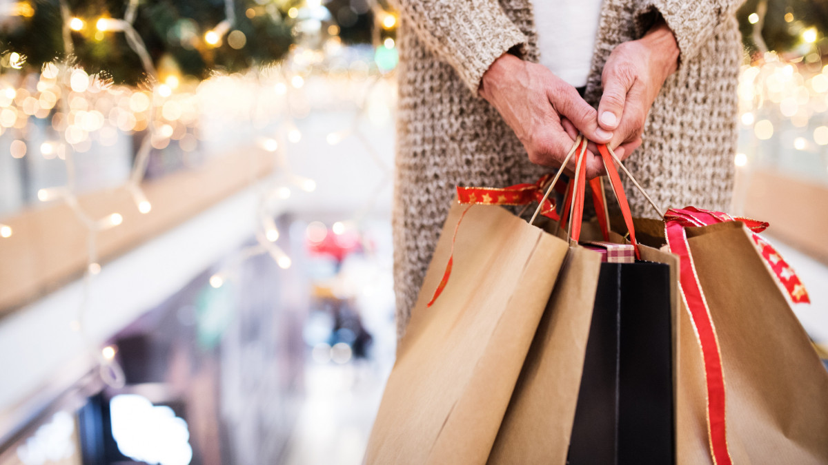 Unrecognizable senior woman with paper bags doing Christmas shopping. Shopping center at Christmas time.