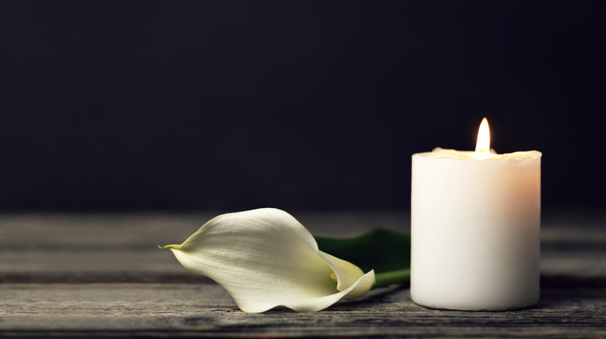 Burning candle and white calla on dark background with copy space. Sympathy card