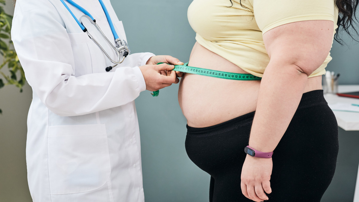 Obesity, unhealthy weight. Nutritionist inspecting a womans waist using a meter tape to prescribe a weight loss diet