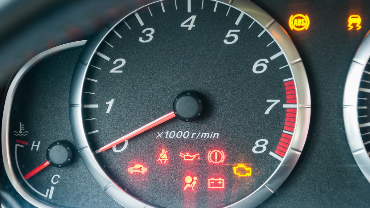 Closeup of car tachometer with many illuminated indicators