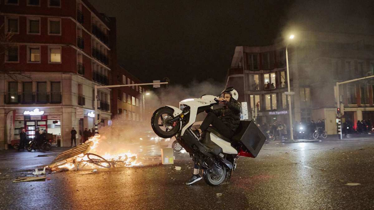 THE HAGUE, NETHERLANDS - NOVEMBER 20: A man performs a wheely with his scooter as riots erupt amid new COVID-19 restrictions on November 20, 2021 in The Hague, Netherlands. (Photo by Pierre Crom/Getty Images)