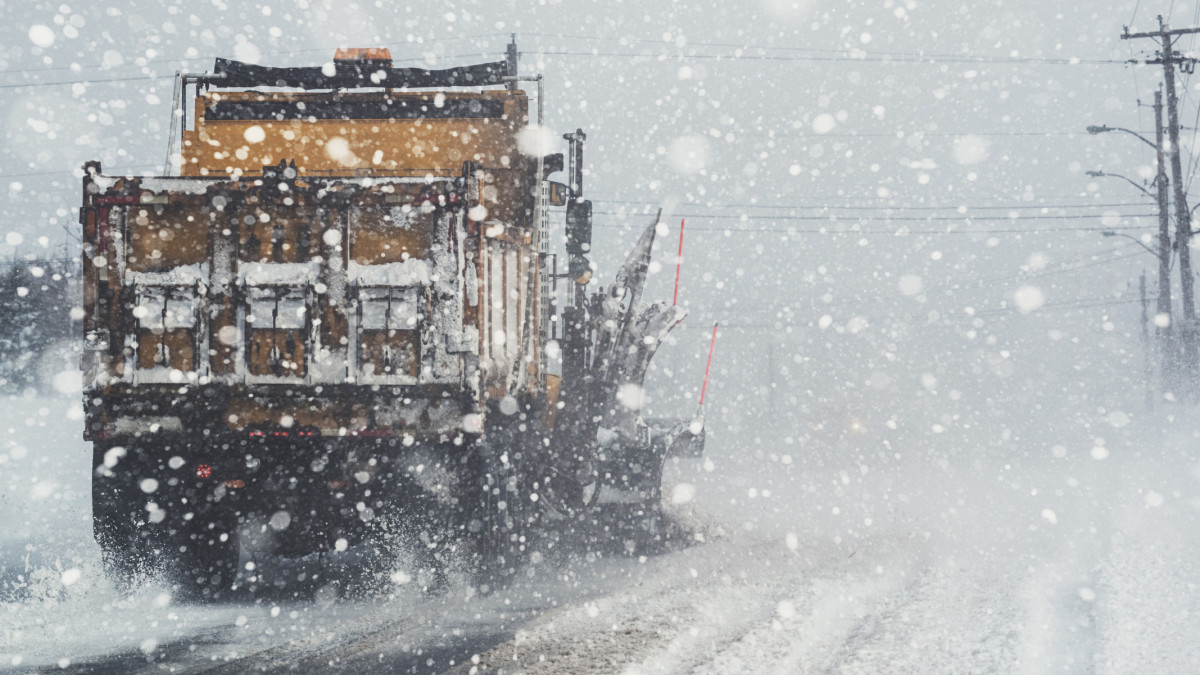 A snowplow clears a city street during a very heavy snowfall.