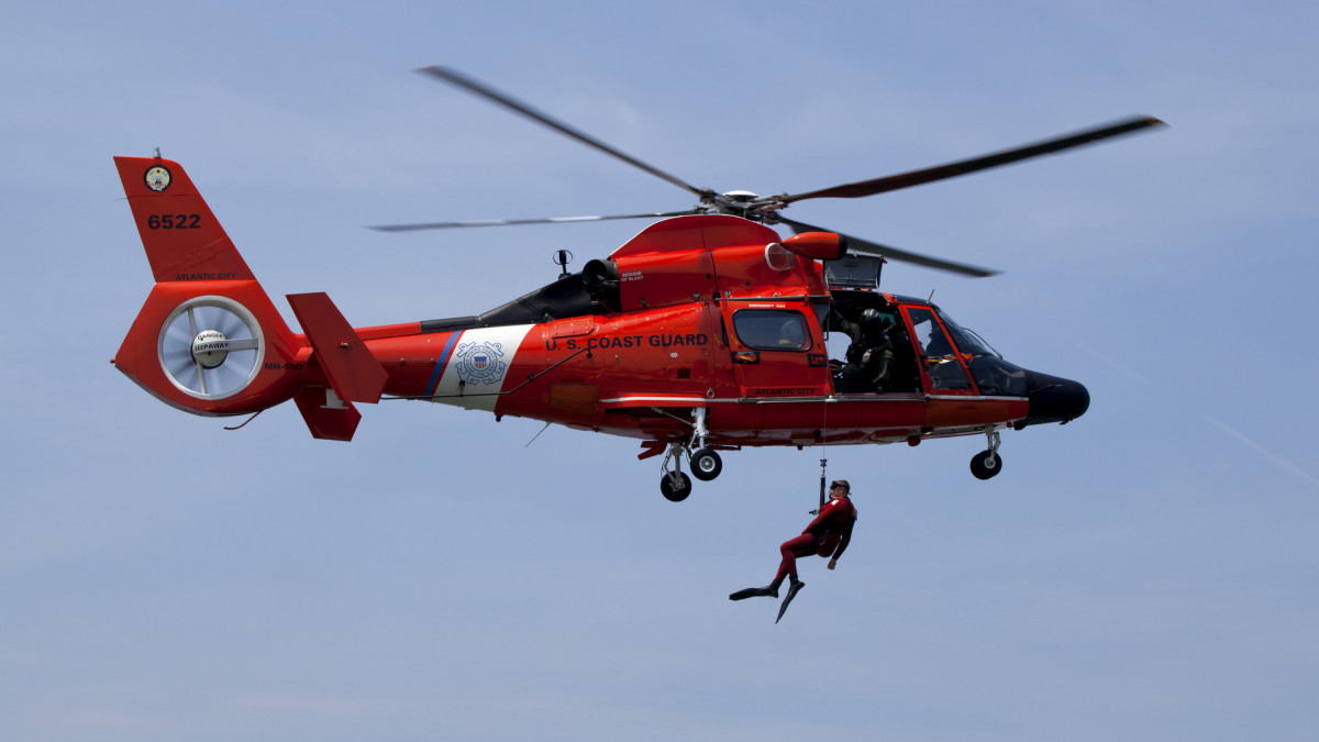 Cape May, New Jersey, USA - June 18, 2011: US Coast Guard  MH-65-C Dauphin Rescue helicopter with rescue swimmer being raised from the water in a training exercise.  Helicopter from the Coast Guard Air Station in Atlantic City, New Jersey.