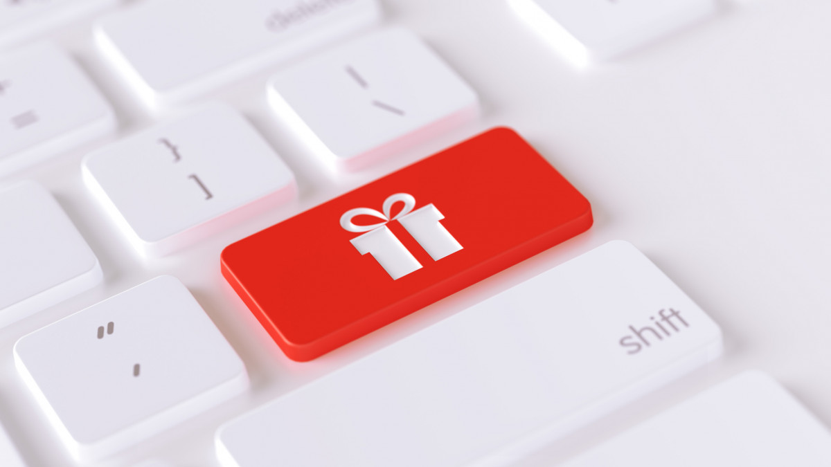 Gift icon written on a red button of a computer keyboard. Horizontal composition with selective focus and copy space. High angle view. Horizontal composition with copy space. Gift concept.