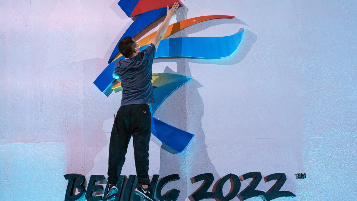 A 2021. szeptember 27-én készült és december 7-én közreadott képen egy dolgozó a falra rögzíti a 2022-es pekingi téli olimpia emblémájának egyik elemét az olimpia arculatát bemutató ünnepség kezdete előtt Pekingben. A washingtoni Fehér Ház 2021. december 6-án bejelentette, hogy az Egyesült Államok egyetlen diplomáciai képviselőt sem küld a 2022. évi téli pekingi olimpiai és paralimpiai játékokra a kínai Hszincsiang-Ujgur tartományban folyó népirtás és emberiesség elleni bűncselekmények miatt.