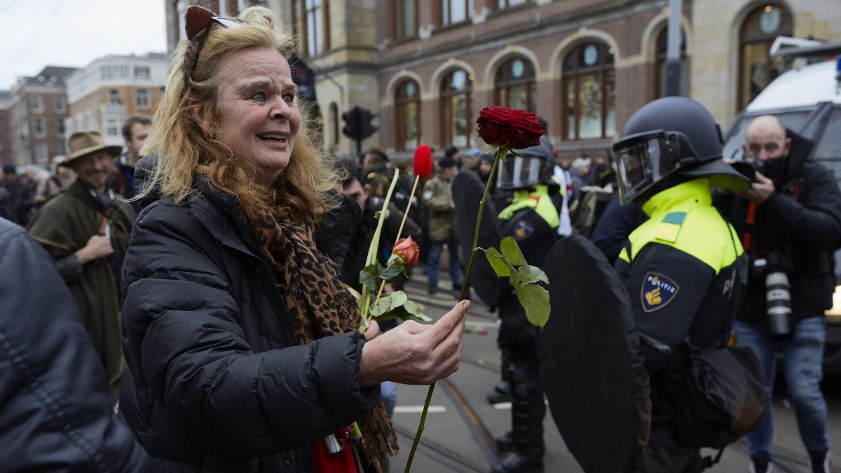 AMSTERDAM, NETHERLANDS - JANUARY 02: A woman crying holds a rose as clashes erupt between police anti-riot officers and antivaxxers affiliated to far-right parties near Museumplein on January 2, 2022 in Amsterdam, Netherlands. With riot police expected to be on strike, authorities have  banned the Covid-19 lockdown protest in the Dutch capital. The postponed police protest is part of a series of strikes by police union members to draw attention to police capacity problems and conditions of work. (Photo by Pierre Crom/Getty Images)