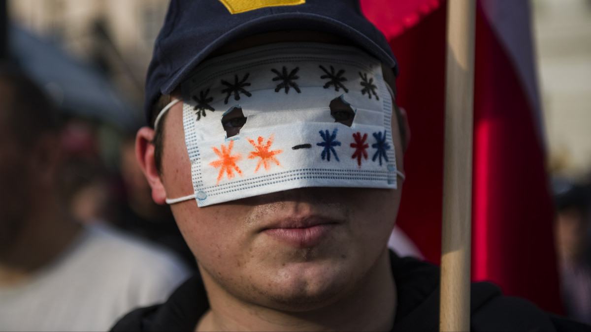 WARSAW, MASOVIA, POLAND - 2021/09/15: A protester wearing a surgical mask on his eyes takes part during the demonstration.Hundreds of people gathered outside the parliament in Warsaw to participate in a protest entitled Stop Sanitary Segregation organized by the Confederation (Konfederacja) far-right nationalist political party. Participants wanted to oppose sanitary segregation, coercion of COVID-19 vaccinations and the new Law 1449 - it is about the act on preventing and combating infections and infectious diseases in humans, which provides, inter alia, financial penalties for people who lie or conceal certain information during the epidemiological interviews. (Photo by Attila Husejnow/SOPA Images/LightRocket via Getty Images)
