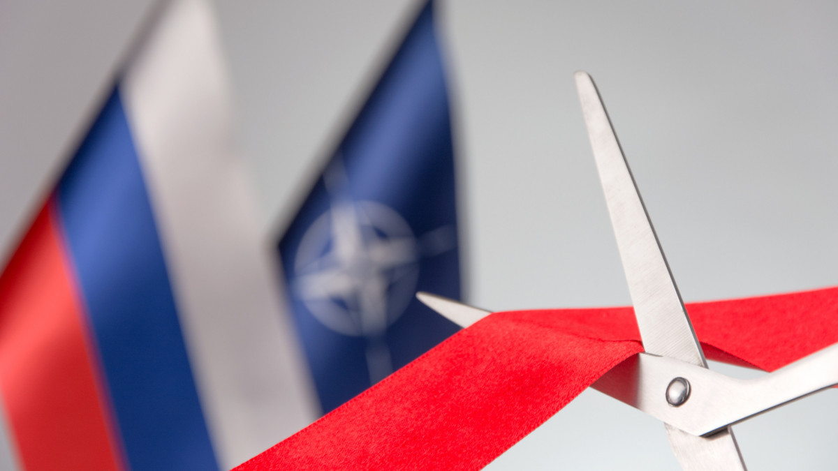 Ribbon cutting ceremony. Scissors cut red ribbon. nRussian and NATO flag bluered on the background. start of a partnership concept