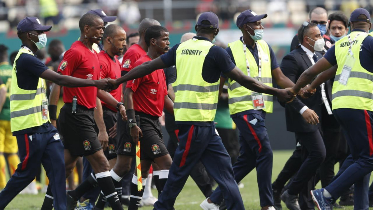 LIMBE, CAMEROON - JANUARY 12: Zambian referee of the match Janny Sikazwe leaves the field accompanied by security after he finished the 2021 Africa Cup of Nations Group F match between Tunisia and Mali before regular time at Omnisport Stadium in Limbe, Cameroon on January 12, 2022. (Photo by Haykel Hmima/Anadolu Agency via Getty Images)