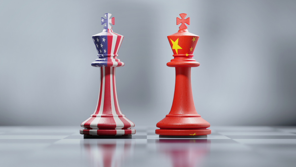 Two king chess pieces textured with American and Chinese flags on black and white chessboard. Politics and checkmate concept. Horizontal composition with selective focus and copy space.