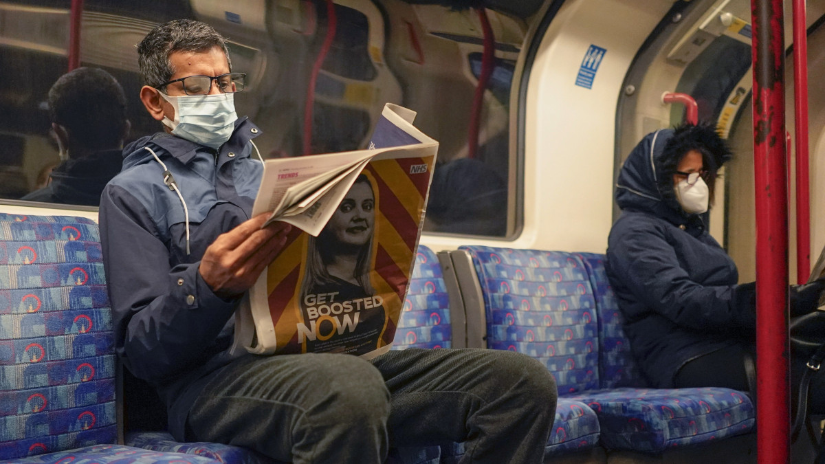 Védőmaszkos utas újságot olvas a londoni metrón 2021. december 16-án. Az előző nap Nagy-Britanniában 78 610 új, koronavírussal fertőzött embert azonosítottak, ez a szám 16 százalékkal magasabb, mint a járvány kitörése óta az eddigi csúcsot jelentő 2021. januári volt.