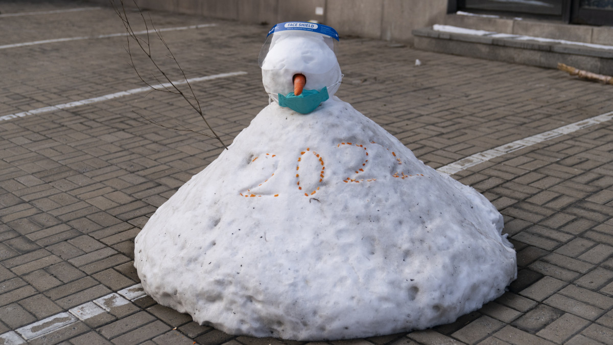 Maszkot és arcvédőt viselő hóember egy pekingi szálloda parkolójában 2022. január 25-én. A kínai fővárosban február 4-20. között rendezik a 2022-es téli ötkarikás játékokat.