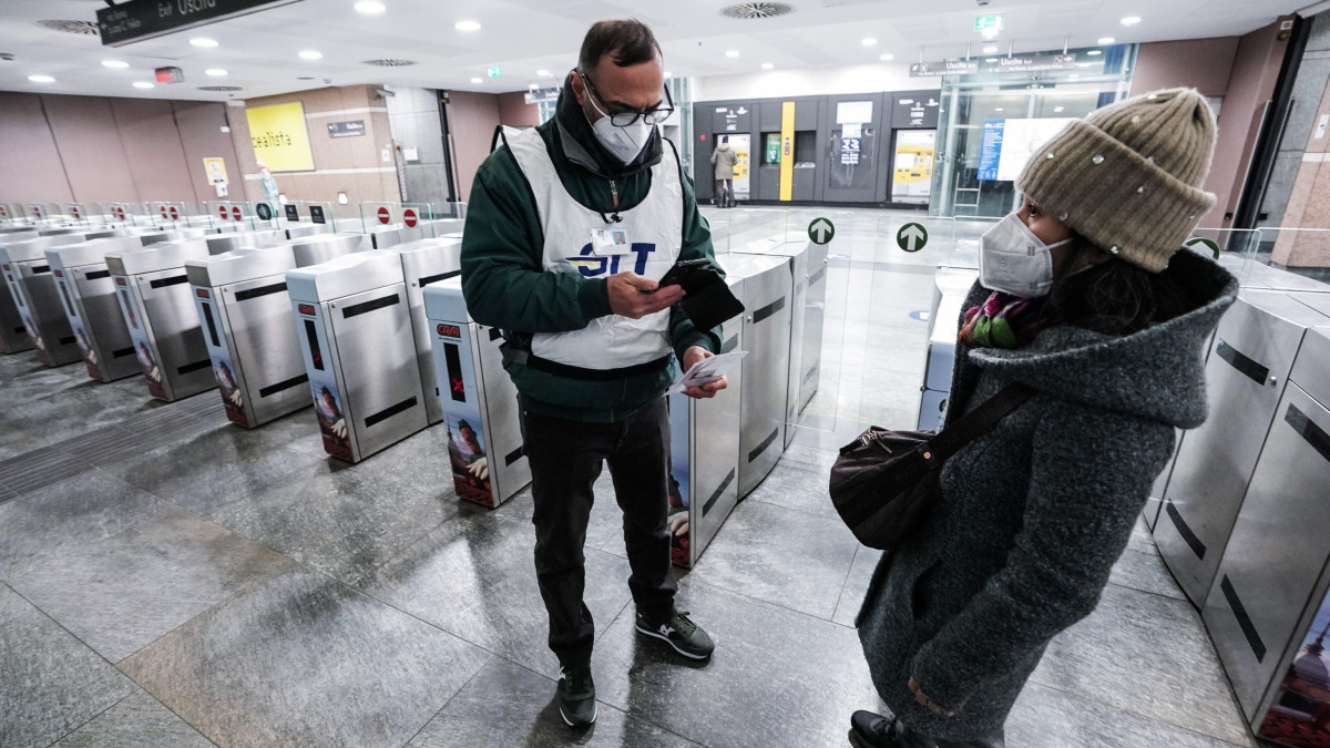 Az utasok oltottságát ellenőrzi a tömegközlekedési vállalat ellenőre egy torinói metróállomáson 2022. január 10-én. Ettől a naptól tilos az új koronavírus elleni oltás nélkül utazni a tömegközlekedési járműveken Olaszországban.