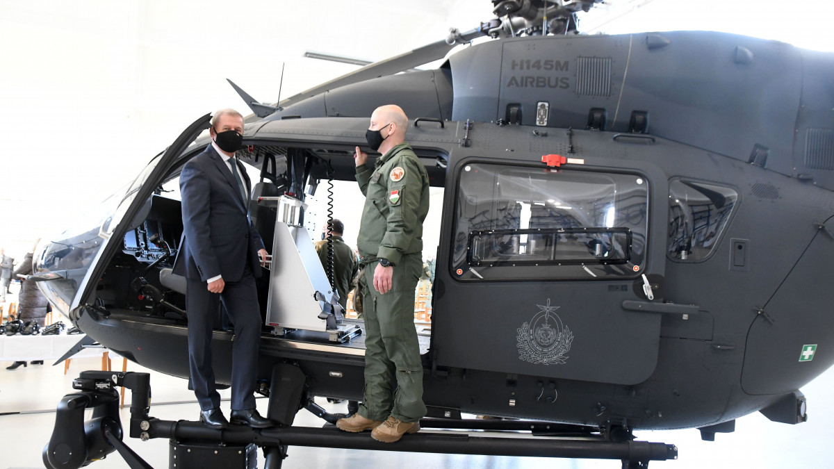 Benkő Tibor (b) honvédelmi miniszter egy katonával beszélget egy helikopteren a Mérföldkő a haderőfejlesztésben? Könnyű helikopter képességcél elérése című rendezvényen az MH 86. Szolnok Helikopter Bázison 2022. február 1-jén. A Zrínyi 2026 honvédelmi és haderőfejlesztési programban teljessé vált a szolnoki bázis H145M többcélú könnyű helikopterflottája, 2021 decemberében megérkezett a szolnoki bázisra a flotta utolsó, huszadik gépe.