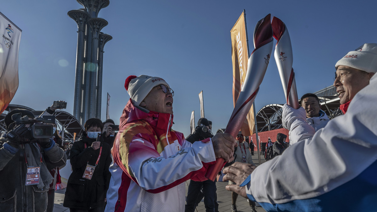 BEIJING, CHINA - FEBRUARY 2: Former World Speed Skating Champion Luo Zhihuan, left, of China lights the torch of Chinese Astronaut Jing Haipeng after running the first leg during the launch ceremony for the Beijing 2022 Winter Olympics Torch Relay in front of the Olympic Tower outside of the closed loop bubble on February 2, 2022 at Olympic Park in Beijing, China. The games are set to open on February 4th. (Photo by Kevin Frayer/Getty Images)