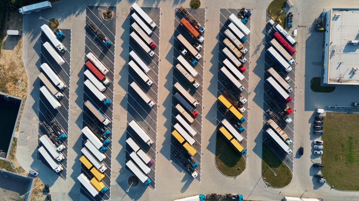 Parking lot for semi trucks, top view. Aerial view of Truck trailers parked for waiting loading on factory. Logistics and shipping