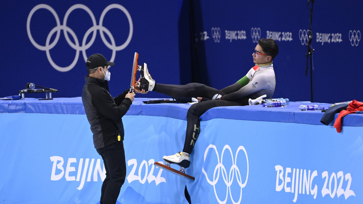 Csun Dzse Szu javítja Liu Shaolin Sándor korcsolyáját a magyar rövidpályás gyorskorcsolya-válogatott edzésén a pekingi téli olimpián, a megnyitóünnepség előtti napon a Fővárosi Fedett Stadionban 2022. február 3-án.