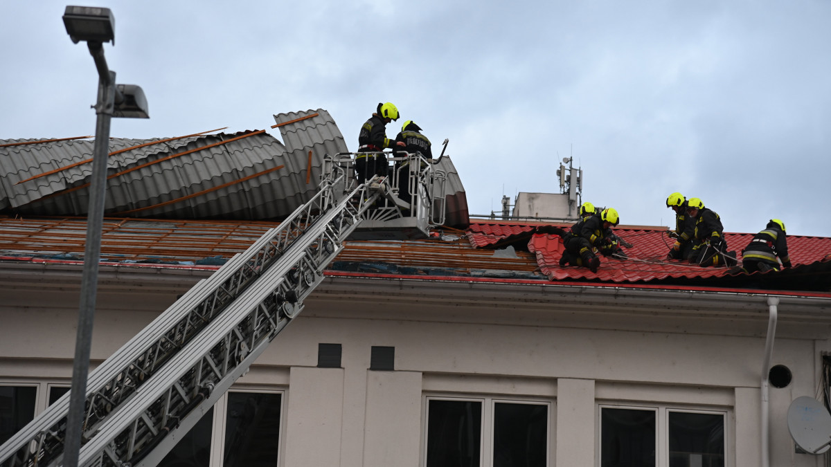 Tűzoltók dolgoznak a főváros XX. kerületében, ahol egy felújítás alatt lévő üzlet tetejéről szakította le a lemezfedést a viharos szél 2022. január 17-én.