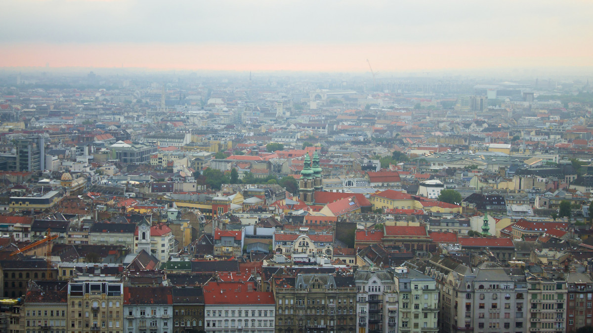 Panorama of foggy or misty morning over european city Budapest, Hungary. Landscape of big old town with gothic or neo gothic architecture at sunrise or sunset in summer. View from above. No people