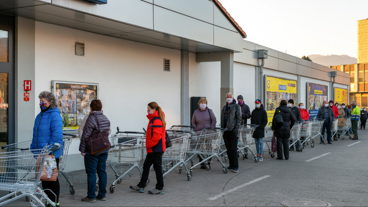 RUZOMBEROK, SLOVAKIA - APRIL 2: Long line of people  with face masks and  shopping cart in front of grocery