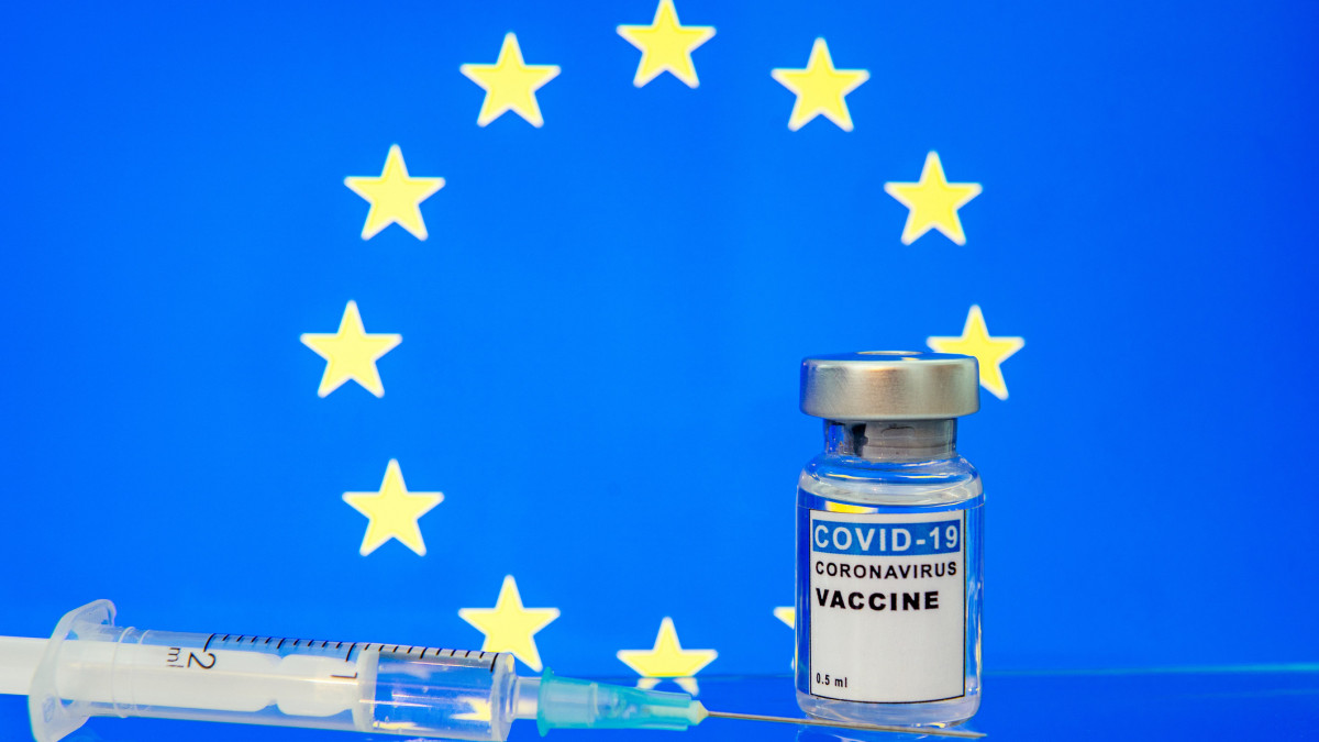 Coronavirus vaccine ready for worldwide administration. Syringe with coronavirus vaccine reflected in glass with European Union flag on background
