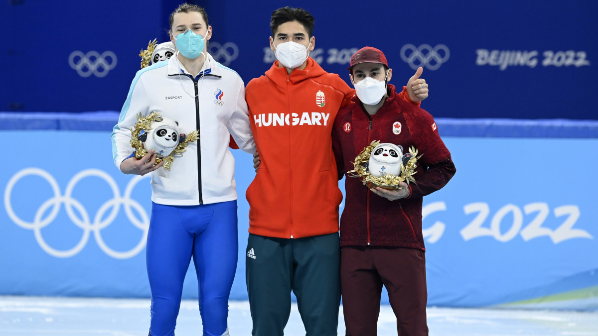 A győztes Liu Shaoang (k), mellette mellette a második helyezett orosz Konsztantyin Ivlijev (b) és a bronzérmes kanadai Steven Dubois a férfi rövidpályás gyorskorcsolyázók 500 méteres versenyének virágceremóniáján a Fővárosi Fedett Stadionban a pekingi téli olimpián 2022. február 13-án.
