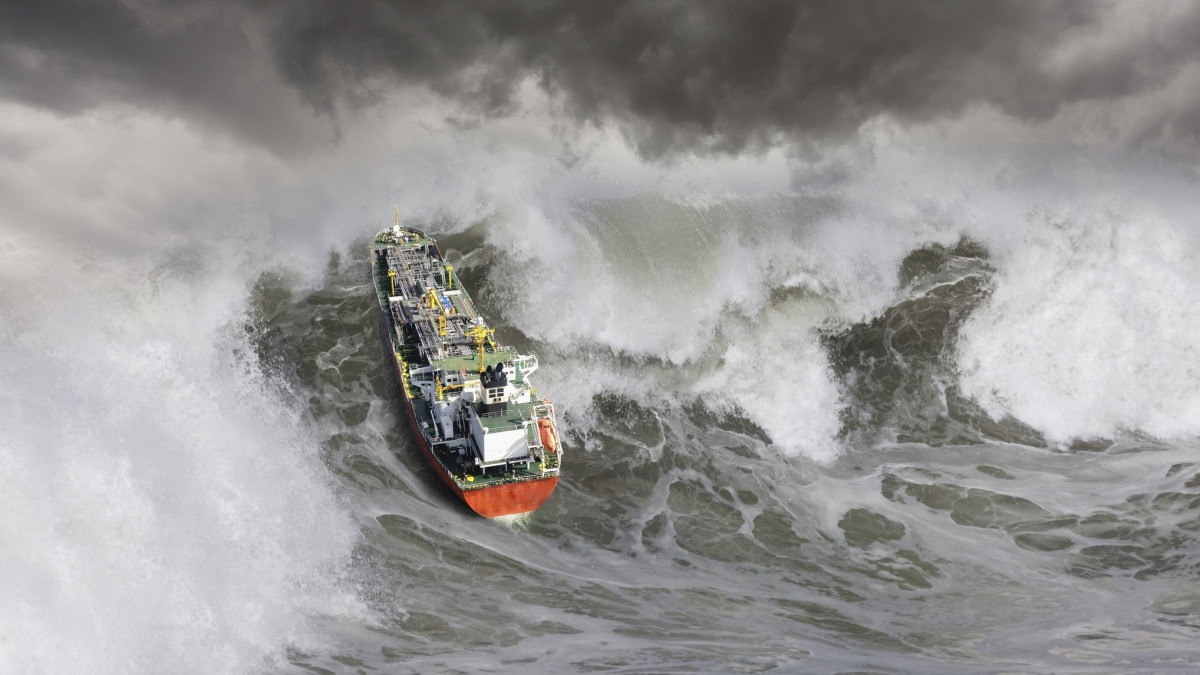 An oil tanker ship churns up a huge tsunami like wave in rough seas.
