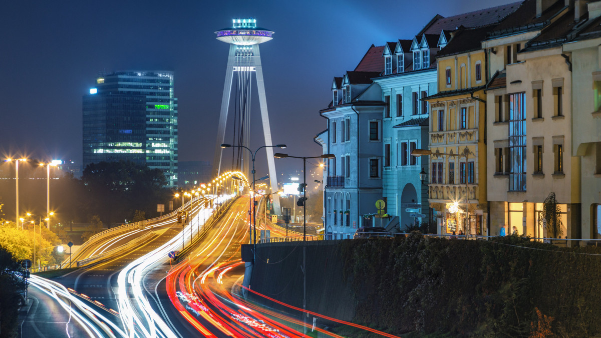 Long exposure cityscape of illuminated Bratislava downtown with light trails on motorway and tall UFO tower at night