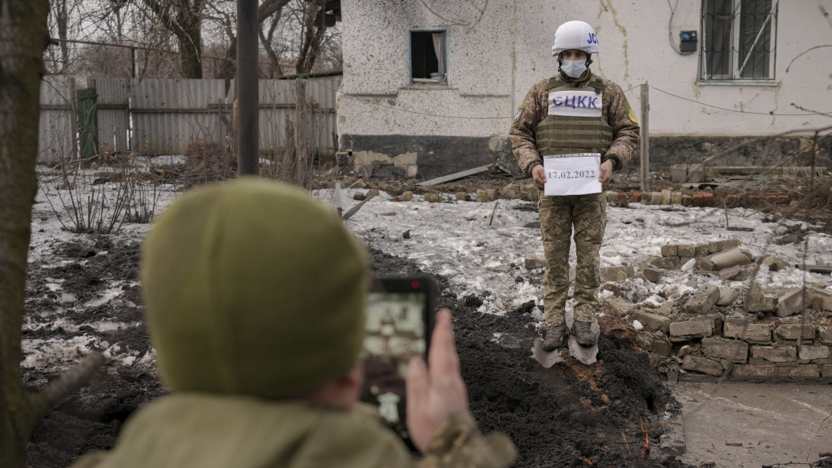 Az orosz-ukrán egyesített ellenőrző és koordináló központ (JCCC) tagjai lefényképeznek egy tüzérségi lövedék által okozott krátert és egy megrongálódott lakóházat a kelet-ukrajnai Luhanszk megyében fekvő Vrubivka közelében 2022. február 17-én. Az orosz kormány által támogatott kelet-ukrajnai szakadárok ezen a napon azzal vádolták a kijevi kormánycsapatokat, hogy az elmúlt 24 órában négyszer nyitottak tüzet a területükre.