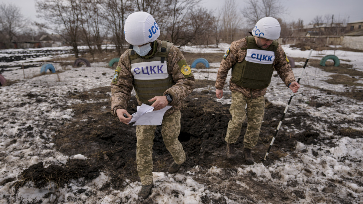 Az orosz-ukrán egyesített ellenőrző és koordináló központ (JCCC) tagjai egy tüzérségi lövedék által okozott krátert vizsgálnak a kelet-ukrajnai Luhanszk megyében fekvő Vrubivka közelében 2022. február 17-én. Az orosz kormány által támogatott kelet-ukrajnai szakadárok ezen a napon azzal vádolták a kijevi kormánycsapatokat, hogy az elmúlt 24 órában négyszer nyitottak tüzet a területükre.