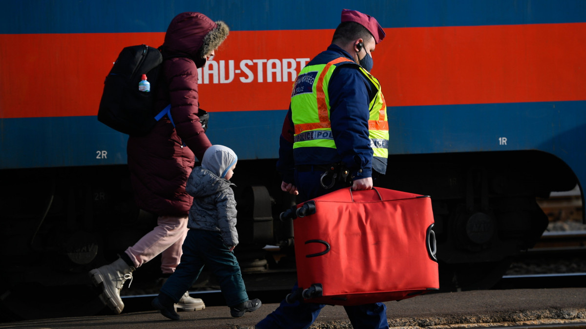 Az orosz-ukrán háború elől menekülő nő bőröndjét viszi egy rendőr a záhonyi vasútállomáson 2022. március 1-jén. 
