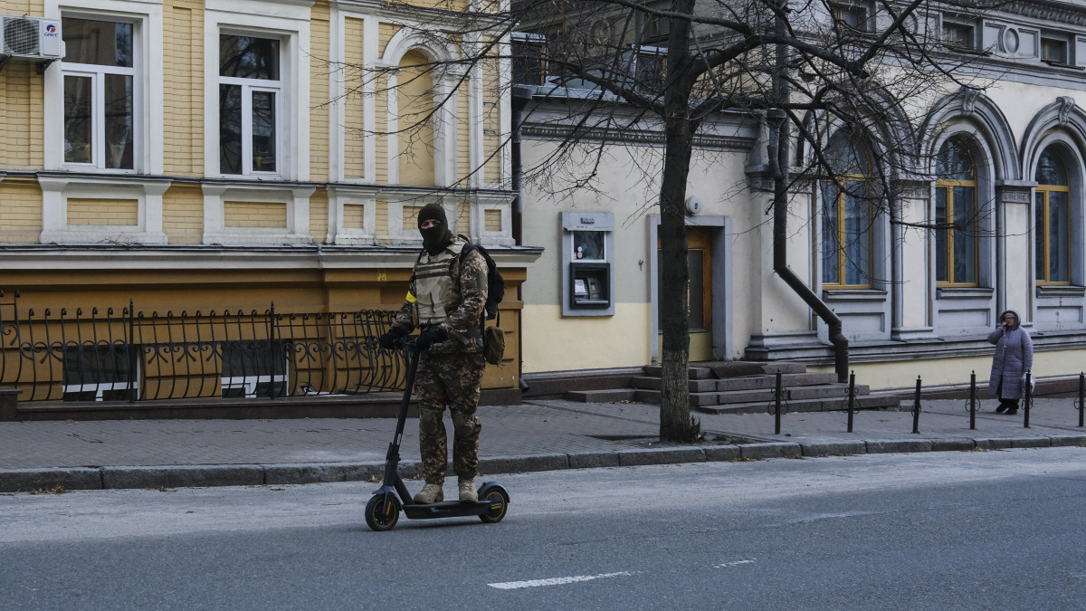 Elektromos rolleren utazik egy fegyveres férfi egy elnéptelenedett utcán Kijevben 2022. március 10-én. Vlagyimir Putyin orosz elnök február 24-én rendelte el katonai művelet végrehajtását Ukrajnában.