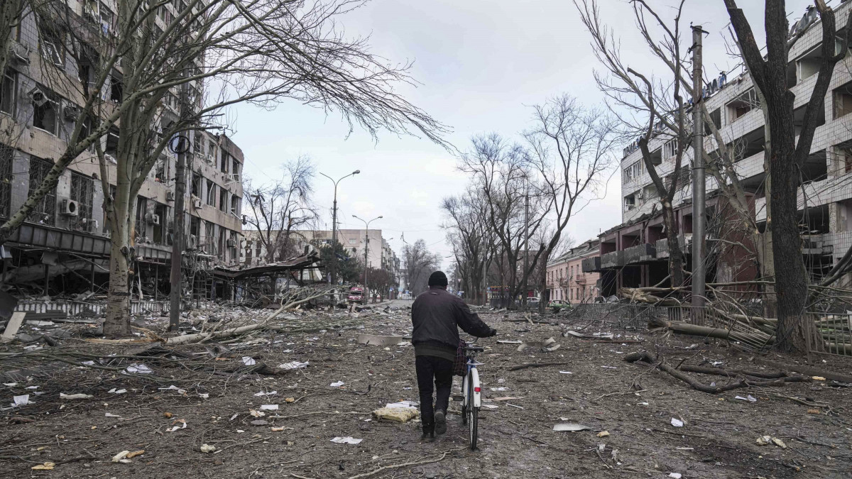 Megrongálódott lakóépületek romjai között tolja kerékpárját egy férfi a délkelet-ukrajnai Mariupolban2022. március 10-én. Vlagyimir Putyin orosz elnök február 24-én rendelte el katonai művelet végrehajtását Ukrajnában.