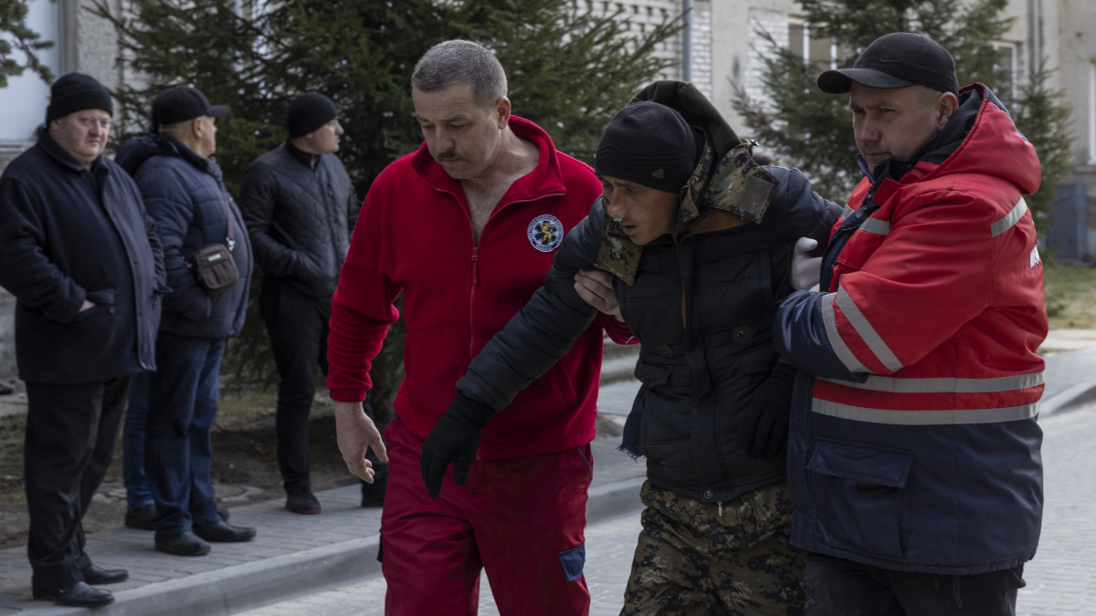 NOVOIAVORISK, UKRAINE - MARCH 13: A man wounded in this mornings air strikes at a nearby military complex is assisted by medical staff outside Novoiavorivsk District Hospital on March 13, 2022 in Novoiavorivsk, Ukraine. Early this morning, a series of Russian missiles struck the International Center for Peacekeeping and Security at the nearby Yavoriv military complex, killing at least 35 and wounding scores, according to Ukrainian officials. The site is west of Lviv and mere miles from Ukraines border with Poland, a NATO member. (Photo by Dan Kitwood/Getty Images)