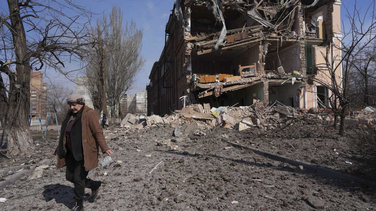 Nő halad el egy tüzérségi támadásban megrongálódott épület előtt Mariupolban 2022. március 13-án. Vlagyimir Putyin orosz elnök február 24-én rendelte el katonai művelet végrehajtását Ukrajnában.