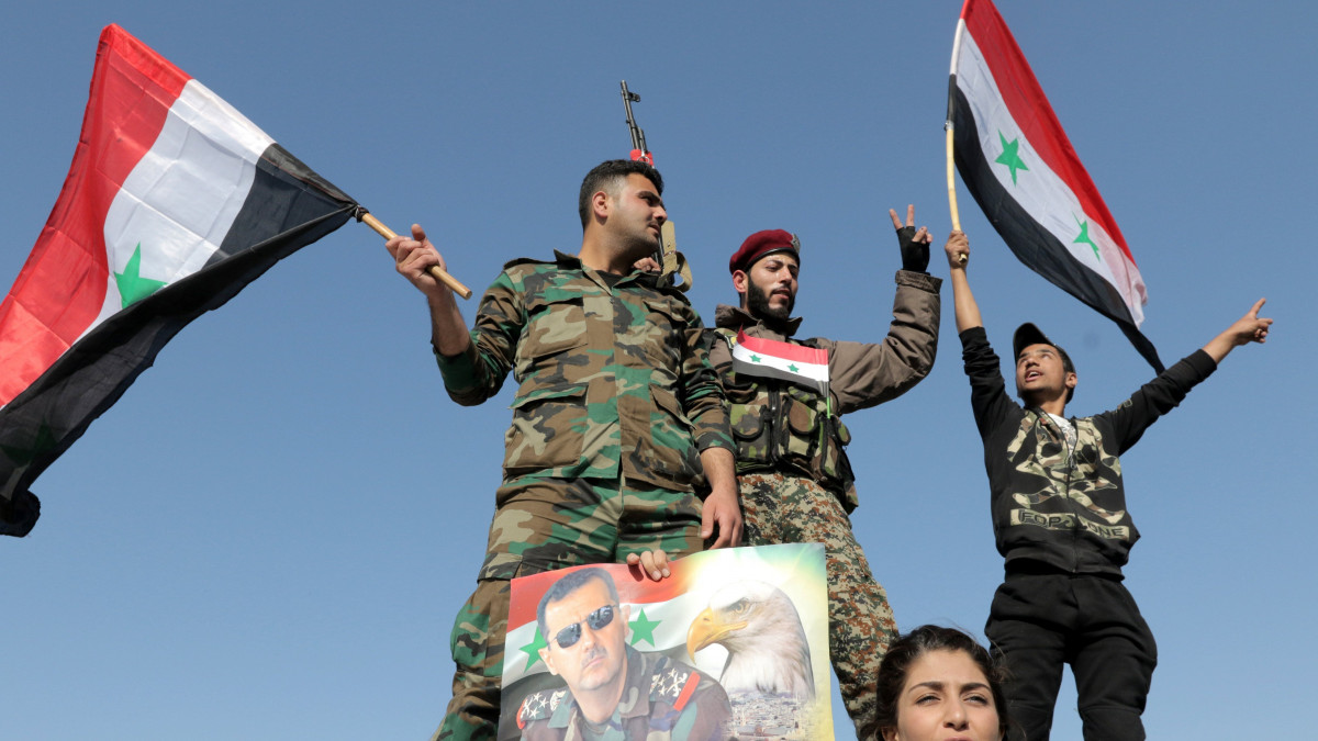 Damaszkusz, 2018. április 14.Szíriai zászlót lengető katonák Bassár el-Aszad szíriai elnököt ábrázoló plakáttal Damaszkuszban 2018. április 14-én, a szíriai kormány melletti szimpátiatüntetésen. Hajnalban amerikai, brit és francia harci gépek célzott légicsapásokat hajtottak végre szíriai feltételezett vegyifegyver-raktárak ellen, válaszul az április 7-én a kelet-gútai Dúma városában elkövetett vegyifegyver-támadásra. (MTI/EPA/Juszef Badaui)