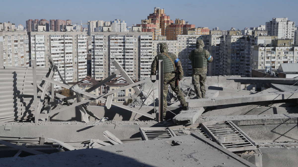 Ukrán katonák vizsgálják egy rakétatámadásban megrongálódott lakóház tetejét Kijevben 2022. március 17-én. Vlagyimir Putyin orosz elnök február 24-én rendelte el katonai művelet végrehajtását Ukrajnában.