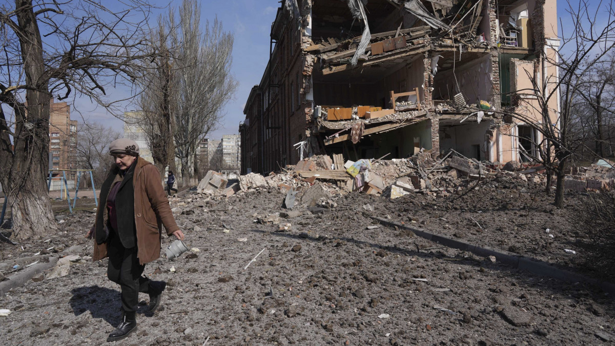 Nő halad el egy tüzérségi támadásban megrongálódott épület előtt Mariupolban 2022. március 13-án. Vlagyimir Putyin orosz elnök február 24-én rendelte el katonai művelet végrehajtását Ukrajnában.