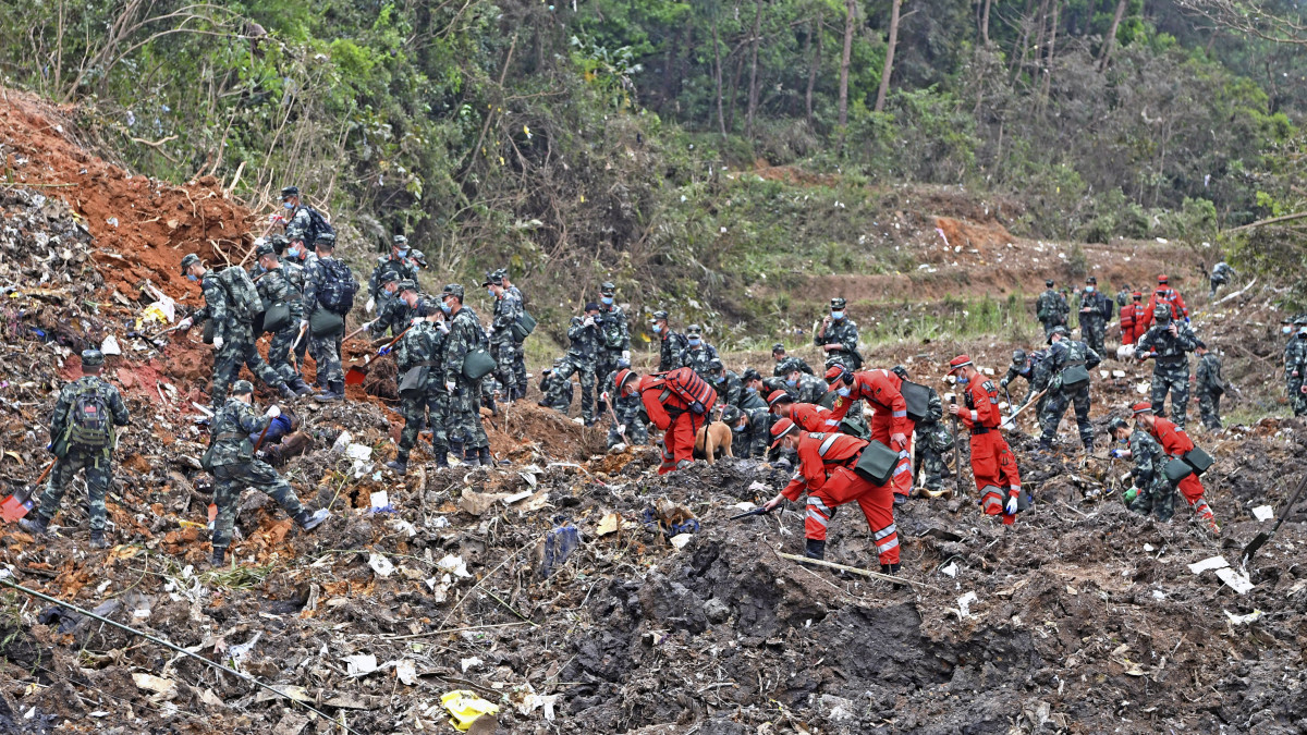 A Hszinhua kínai hírügynökség által közreadott képen mentőalakulatok tagjai kutatnak a China Eastern Airlines kínai légitársaság Boeing 737-es típusú belföldi utasszállítója tragédiájának helyszínén, a dél-kínai Kuanghszi tartományban 2022. március 22-én, egy nappal a repülőgép-szerencsétlenség után. A Kunmingból Kantonba (Kuangcsou) tartó gép fedélzetén 132 emberrel a hegyoldalba csapódott, a balesetnek nincs túlélője.MTI/AP/Hszinhua/Hua Csou