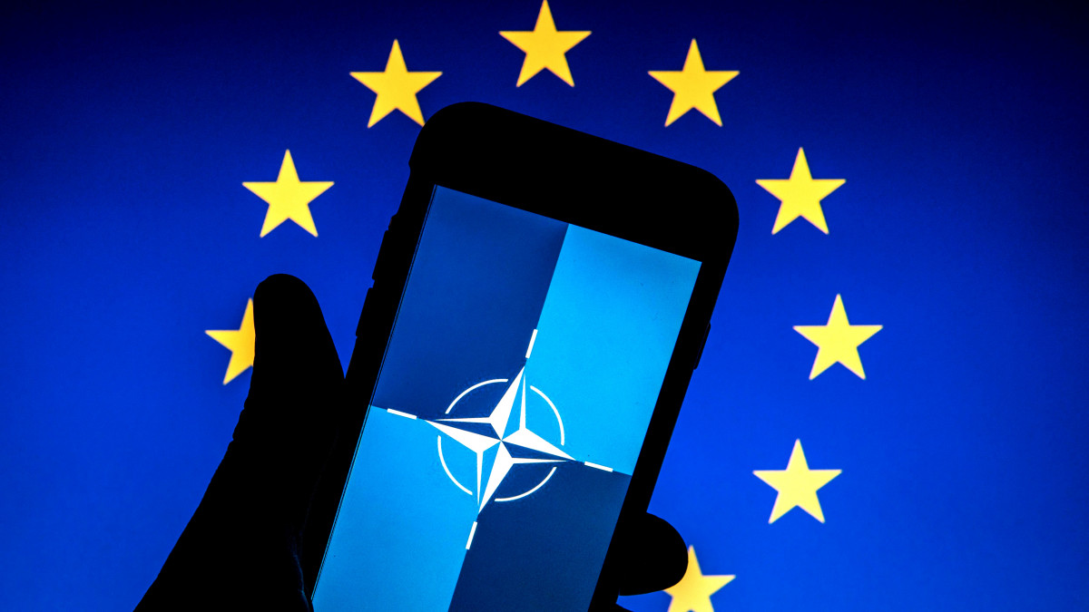 SPAIN - 2022/02/17: In this photo illustration, a NATO (North Atlantic Treaty Organization) flag is seen on a smartphone screen and flag of European Union in the background. (Photo Illustration by Thiago Prudencio/SOPA Images/LightRocket via Getty Images)