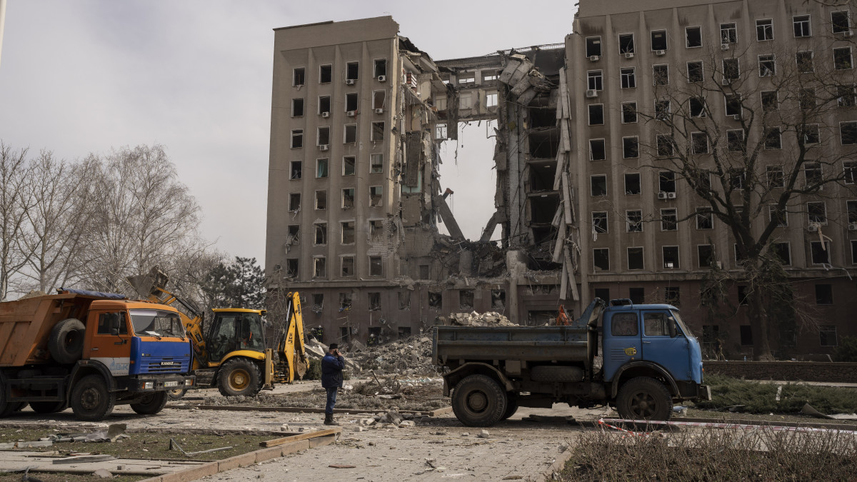 Egy férfi telefonál az orosz légitámadásban megsemmisült helyi kormányépület romjai előtt 2022. március 29-én. Vlagyimir Putyin orosz elnök február 24-én rendelte el katonai művelet végrehajtását Ukrajnában.