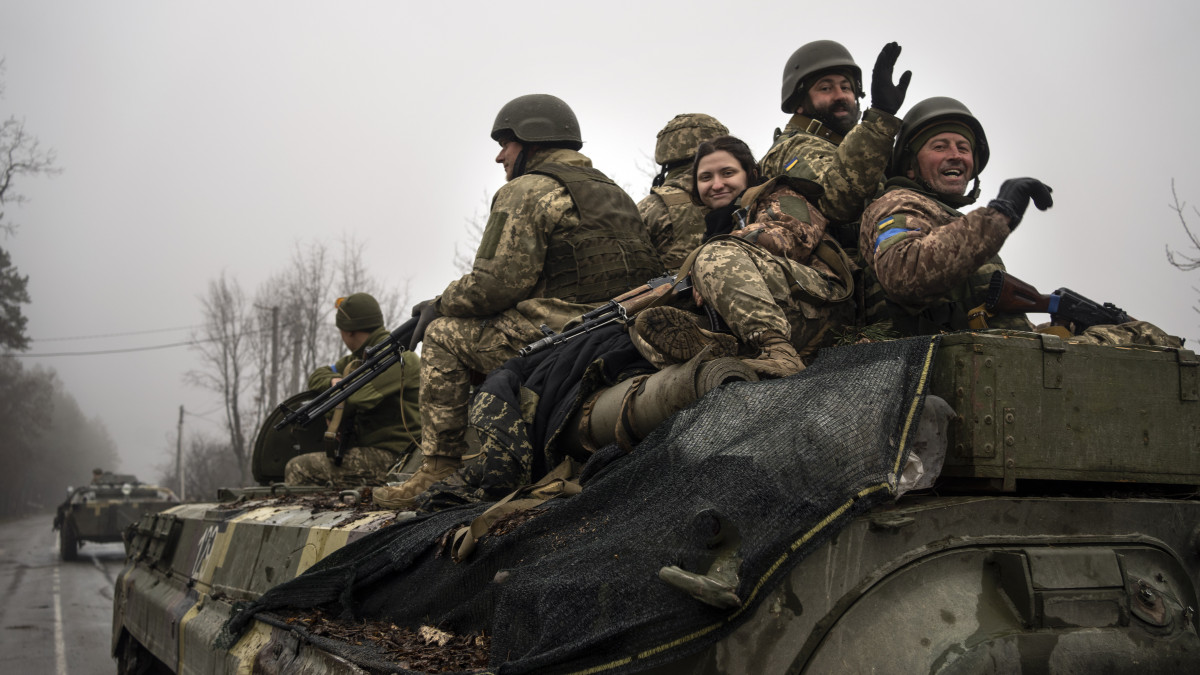 Ukrán katonák intgetnek a fotóriportereknek, miközben  ellenőrzik, hogy valóban minden orosz katona elhagyta-e a Kijev közelében fekvő falvakat 2022. április 1-jén.