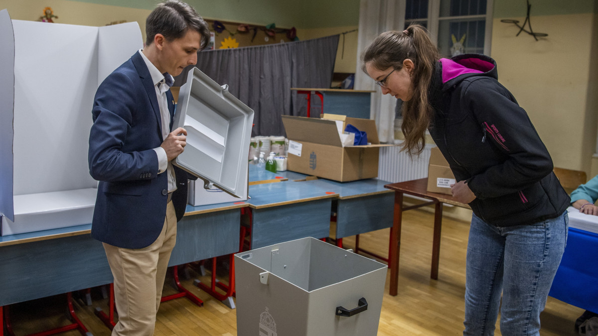 Az első szavazó ellenőrzi az urnákat az Erzsébetvárosi Kéttannyelvű Általános Iskola, Szakgimnázium és Szakközépiskolában kialakított szavazókörben az országgyűlési választáson és gyermekvédelmi népszavazáson 2022. április 3-án.