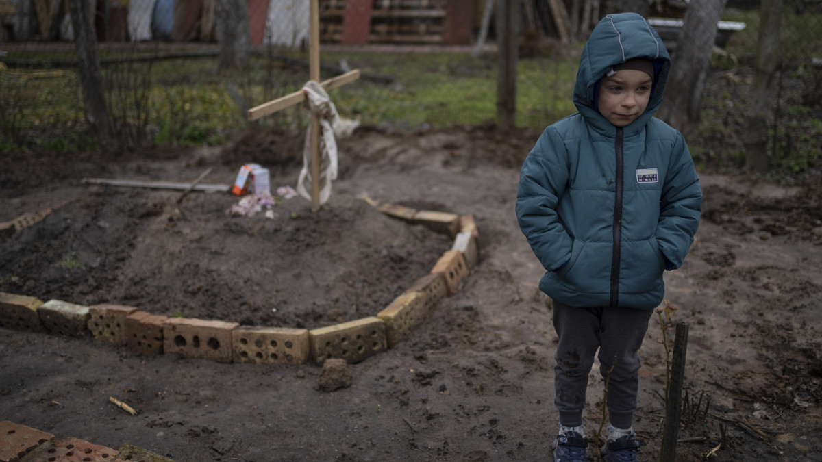 A hatéves Vlad Tanyuk édesanyja, Ira Tanyuk sírja mellett áll Kijev egyik külvárosában 2022. április 4-én. Ira Tanyuk éhen halt.