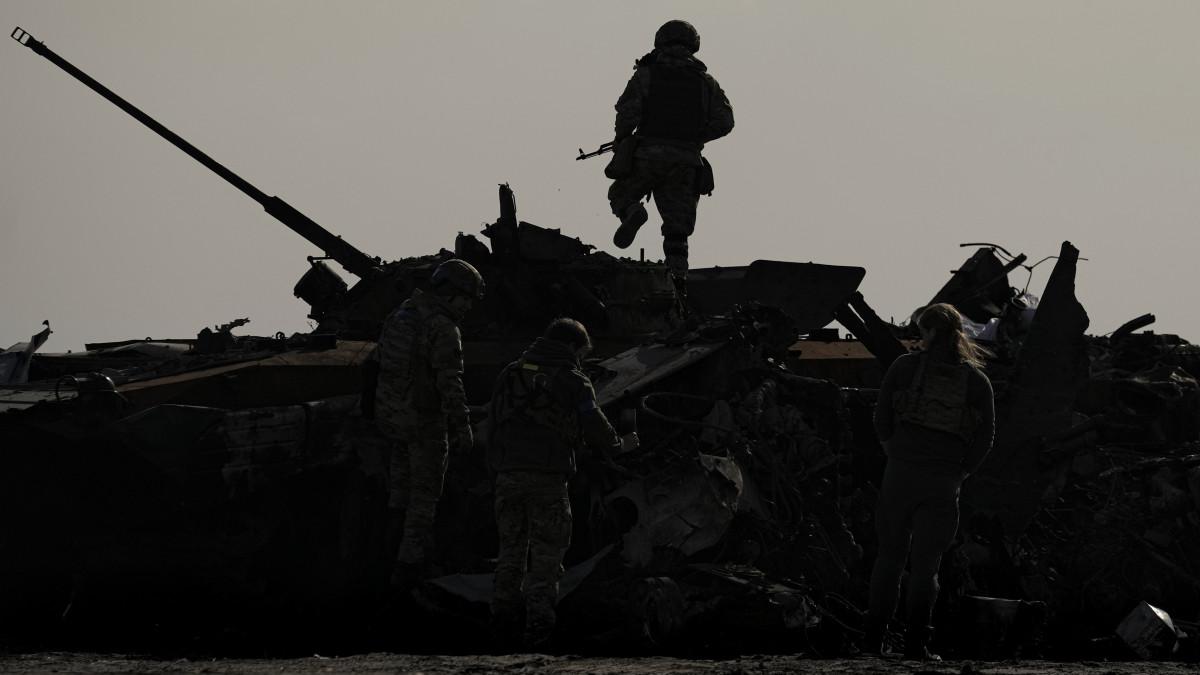 Ukrán katona megy egy megrongálódott orosz katonai jármű tetején Bucsában 2022. április 7-én.